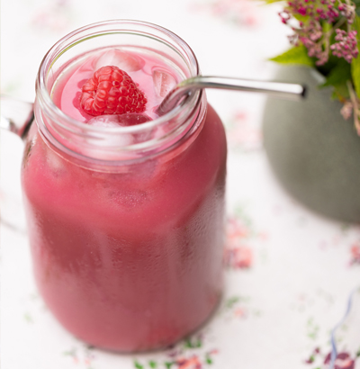 A large transparent glass of an attractive Raspberry Smoothie of a vibrant pink.